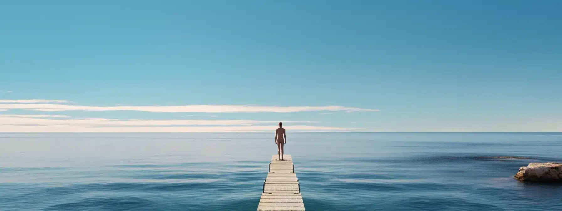 A Person Standing On The Edge Of A Diving Board, Preparing To Dive Into A Vast And Mysterious Ocean.