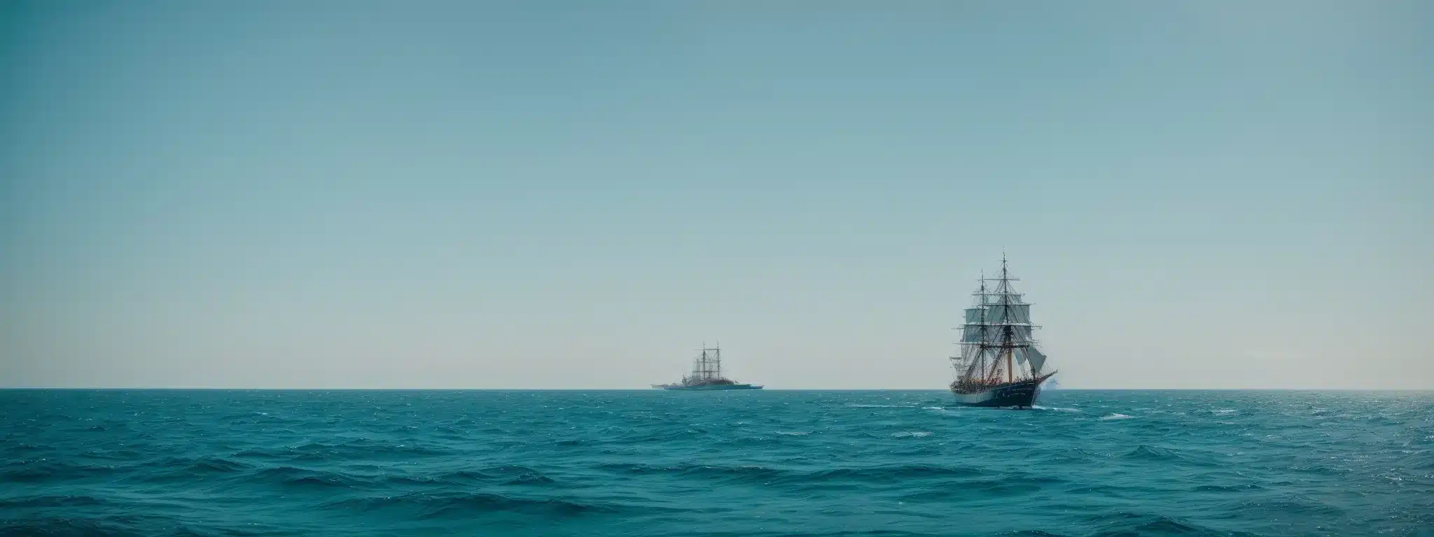 A Vintage Ship Gracefully Navigating Through Tranquil, Glittering Azure Waters Under An Expansive Horizon.
