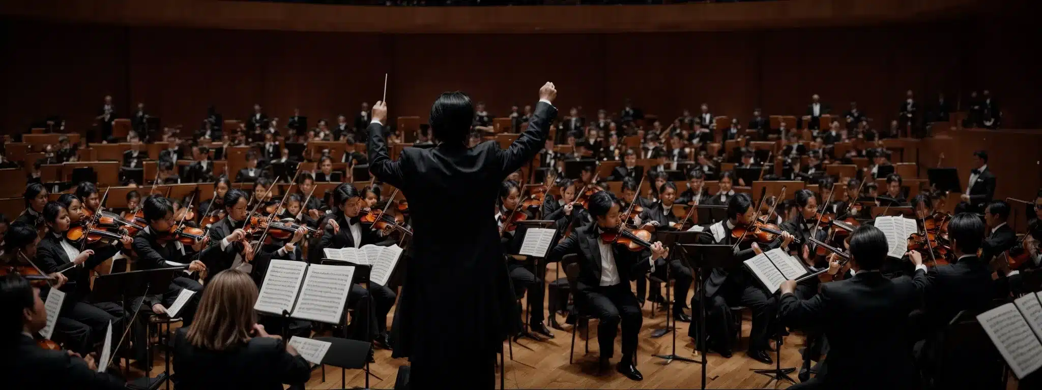 A Conductor With A Baton Stands Before An Engaged Orchestra During A Captivating Performance.