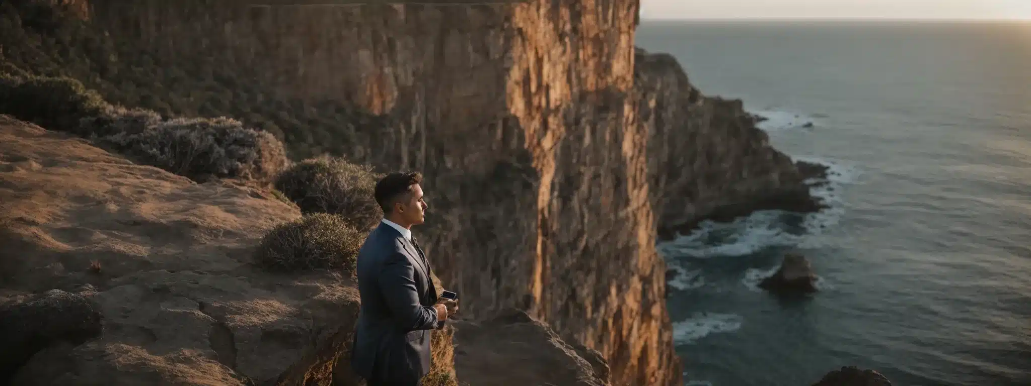 A Businessman With A Compass Standing On A Cliff Looking Out Over A Vast Ocean At Sunrise.